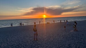Ein Strand bei Sonnenuntergang, Menschen spazieren und entspannen.