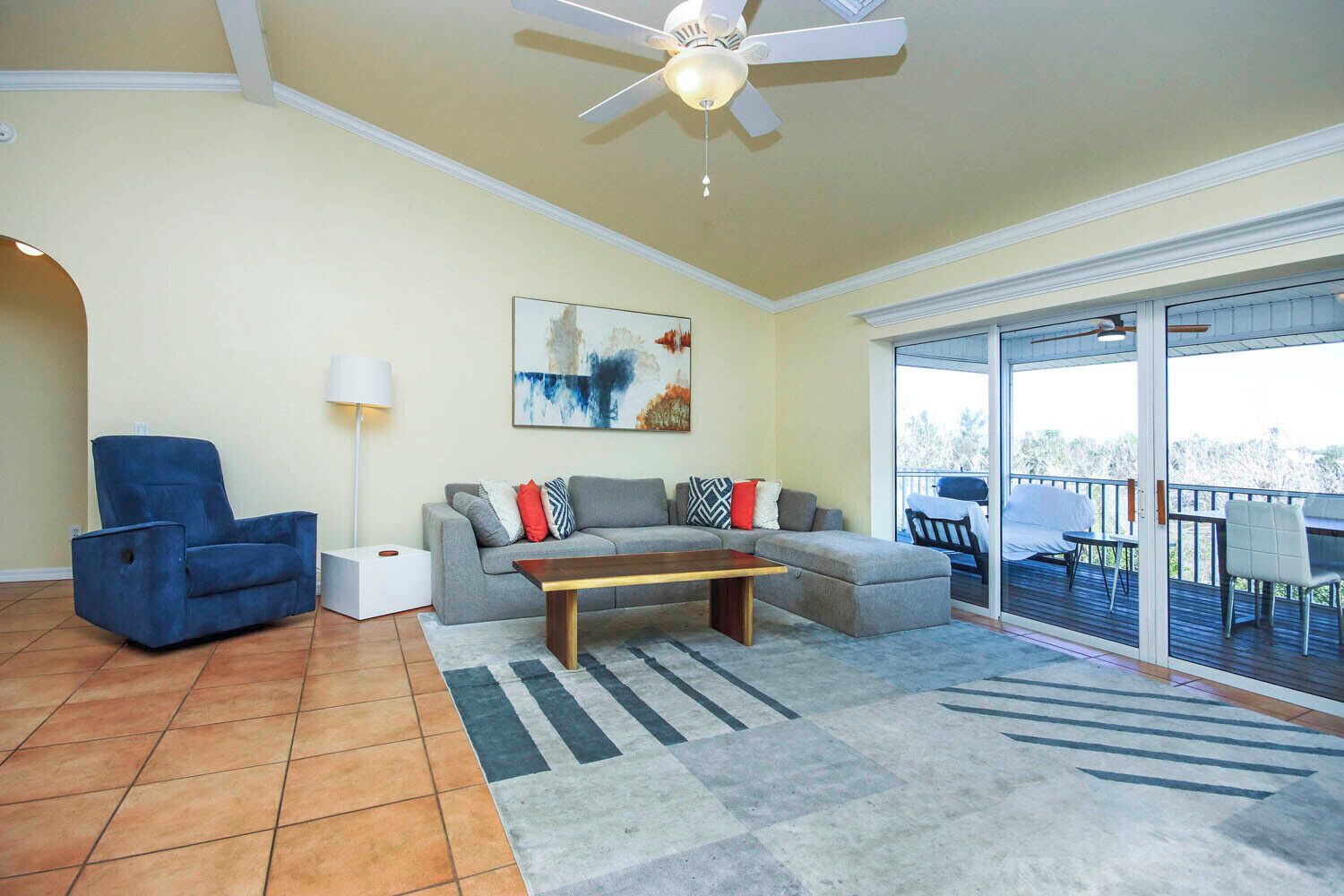 A living room with a sofa, armchair, coffee table, and a ceiling fan.