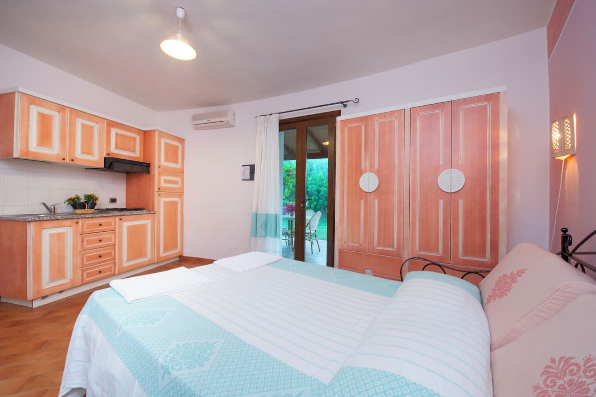 Une chambre à coucher avec un lit, une table de chevet, une fenêtre avec des rideaux et une vue sur l’extérieur.