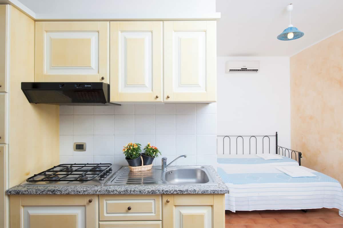 Une cuisine de taille réduite, équipée d’une cuisinière à gaz, d’un évier et de plantes en pot.