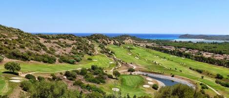 A golf course with multiple holes, a pond, and a view of the ocean.
