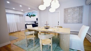 A dining area with a wooden table, four chairs, and a chandelier. - Westshore Luxury (West Haven)