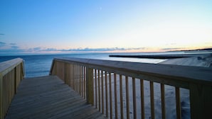 A wooden boardwalk leading to a beach with a clear view of the ocean and a distant shoreline. - Westshore Luxury (West Haven)