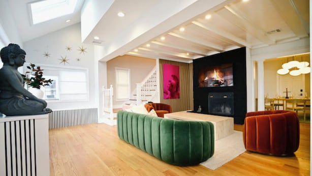 A modern living room with a green sofa, a red ottoman, and a Buddha statue. - Westshore Luxury (West Haven)