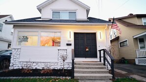 A single-story house with a dark front door, a small porch, and a stone foundation. - Westshore Luxury (West Haven)