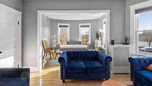 A modern living room with a blue sofa, a yellow armchair, and a grey sofa in the background.