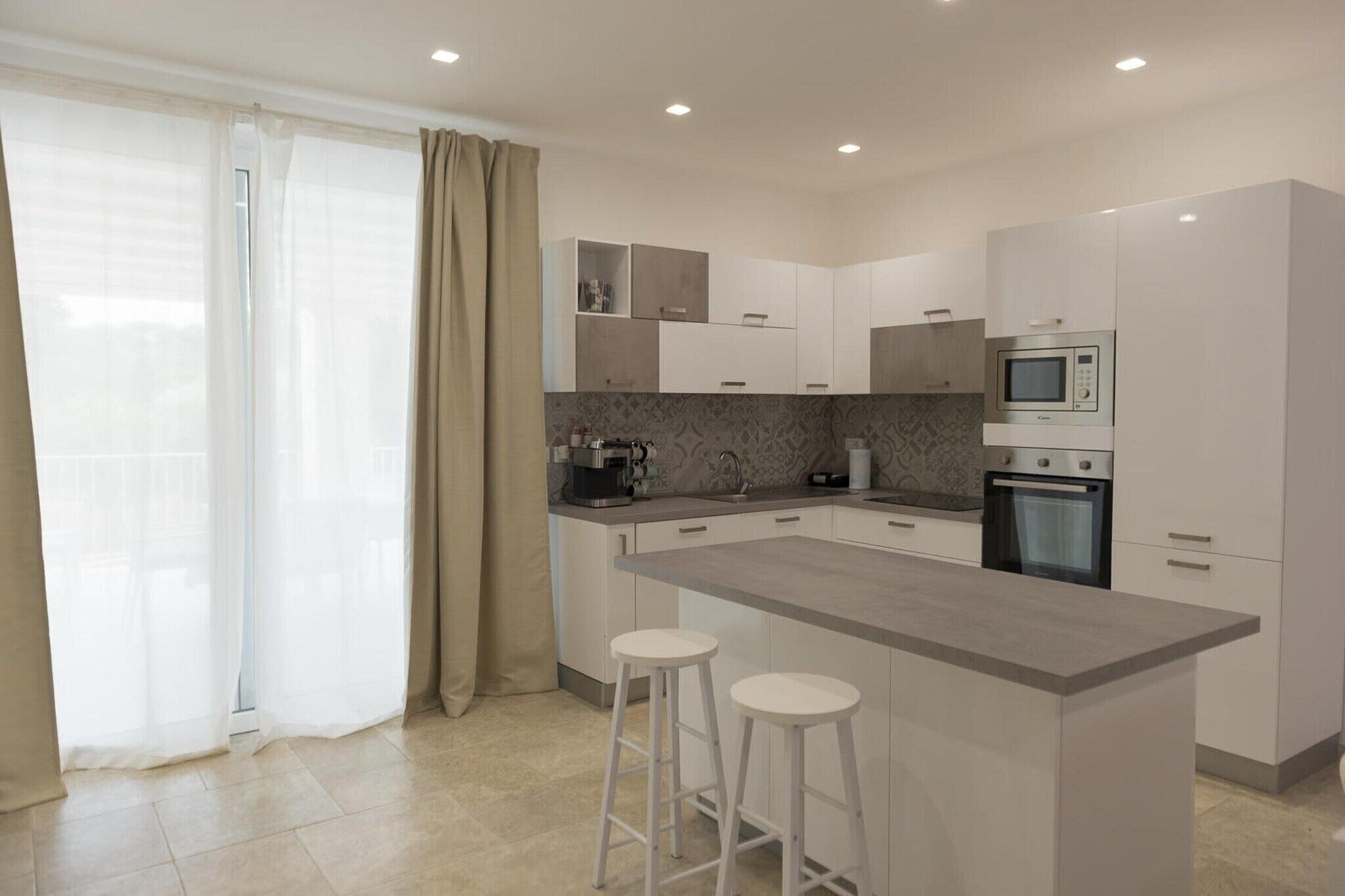A modern kitchen with a central island, bar stools, and built-in appliances.