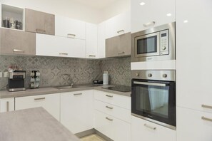 A modern kitchen with white cabinetry, a built-in microwave, and an oven.