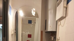 Une petite salle de bain équipée d’un lave-linge, d’un miroir et de toilettes.