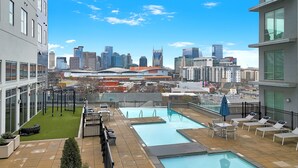 Zona de piscina en la azotea con vistas al horizonte urbano, mobiliario exterior y equipo de ejercicio.