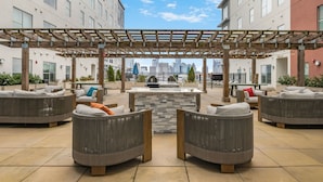 Terraza en la azotea con mobiliario exterior, una chimenea de piedra y vistas a la ciudad.