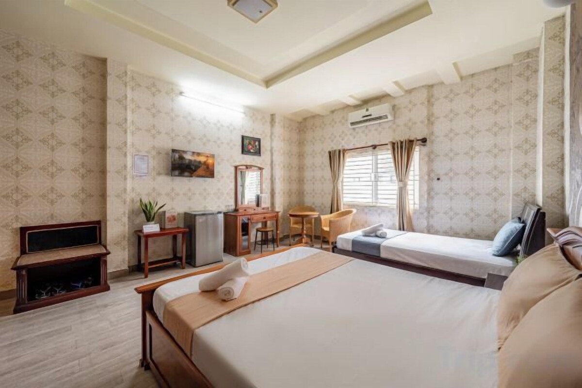 Une chambre d’hôtel avec un grand lit, un bureau, une chaise, une petite table et un téléviseur.
