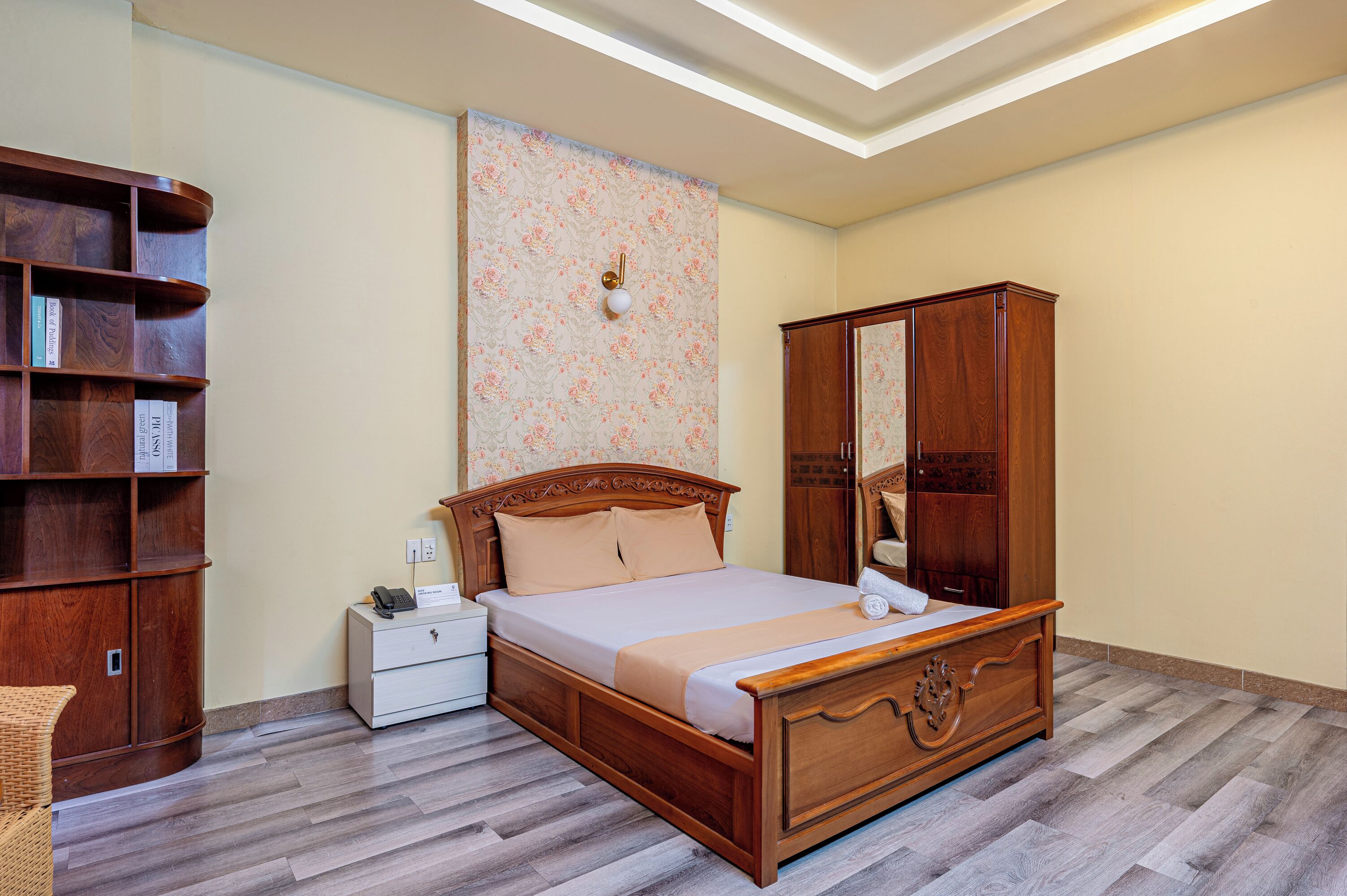 A bedroom with a wooden bed, a nightstand, a wardrobe, and a bookshelf.
