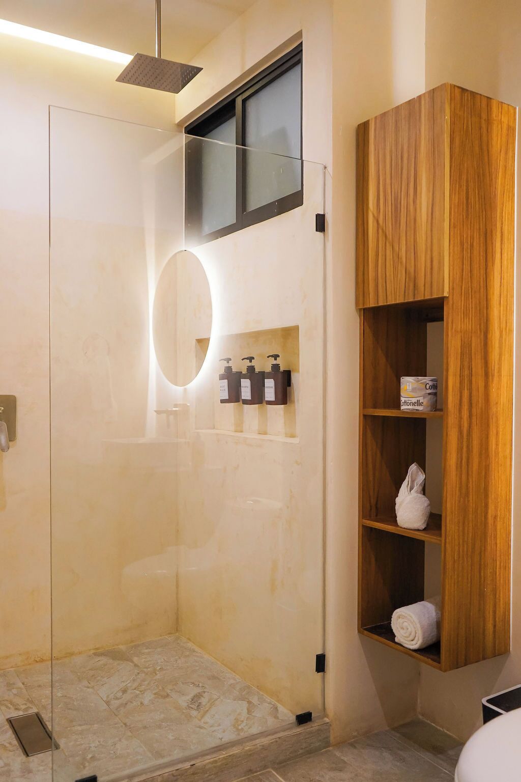 A modern bathroom with a glass shower enclosure, a wooden vanity with shelves, and a mirror.