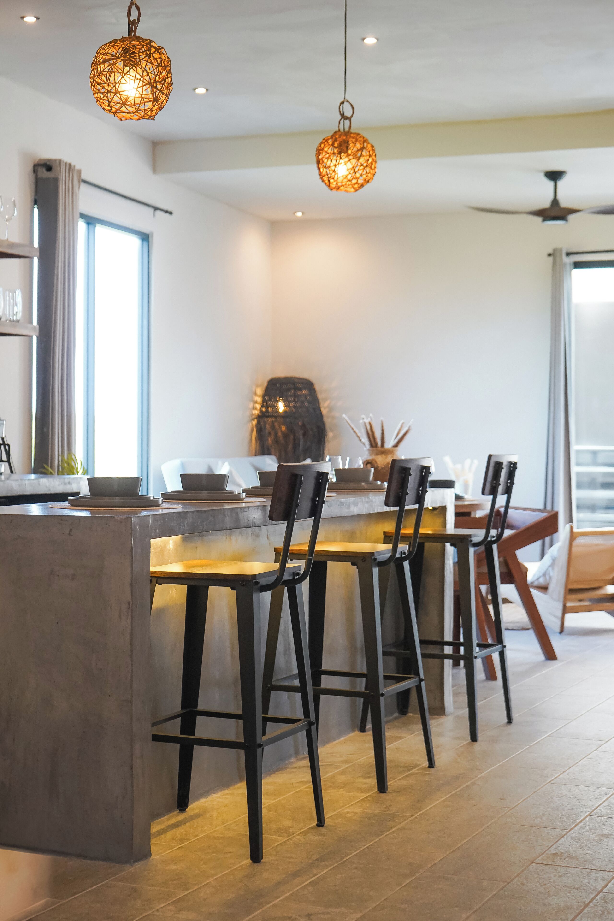 Uma cozinha moderna com ilha central, banquetas e iluminação pendente.