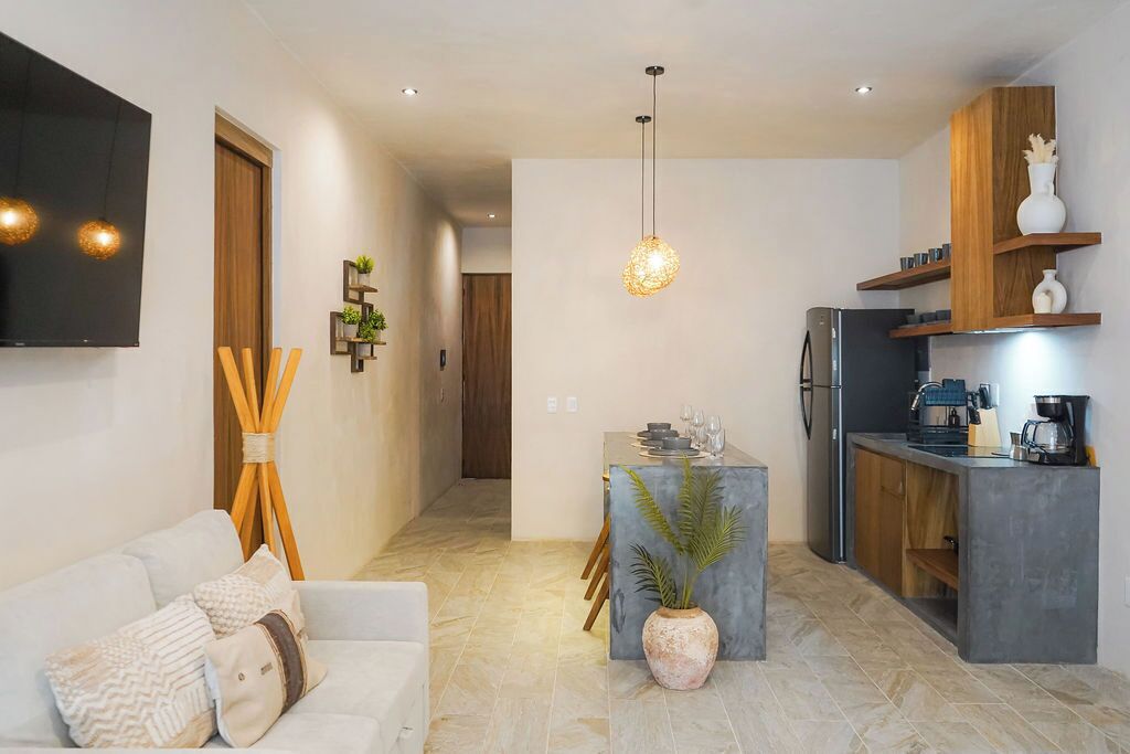 Una cocina moderna con refrigerador integrado, cafetera y zona de comedor con mesa y sillas.