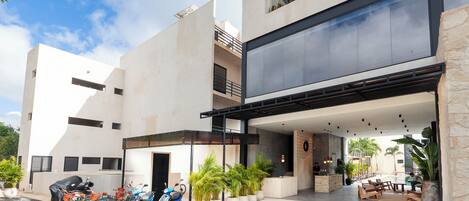 A modern building with a covered outdoor area, multiple ATVs parked outside, and potted plants.