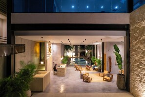 A modern lobby with a reception desk, seating area, and a pool. - Otonomus Tulum (Tulum)
