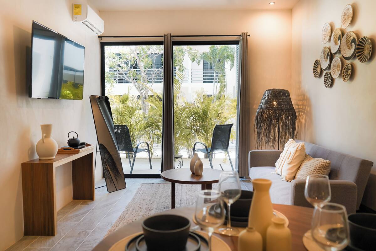 A modern living room with a sofa, a coffee table, and a TV mounted on the wall.
