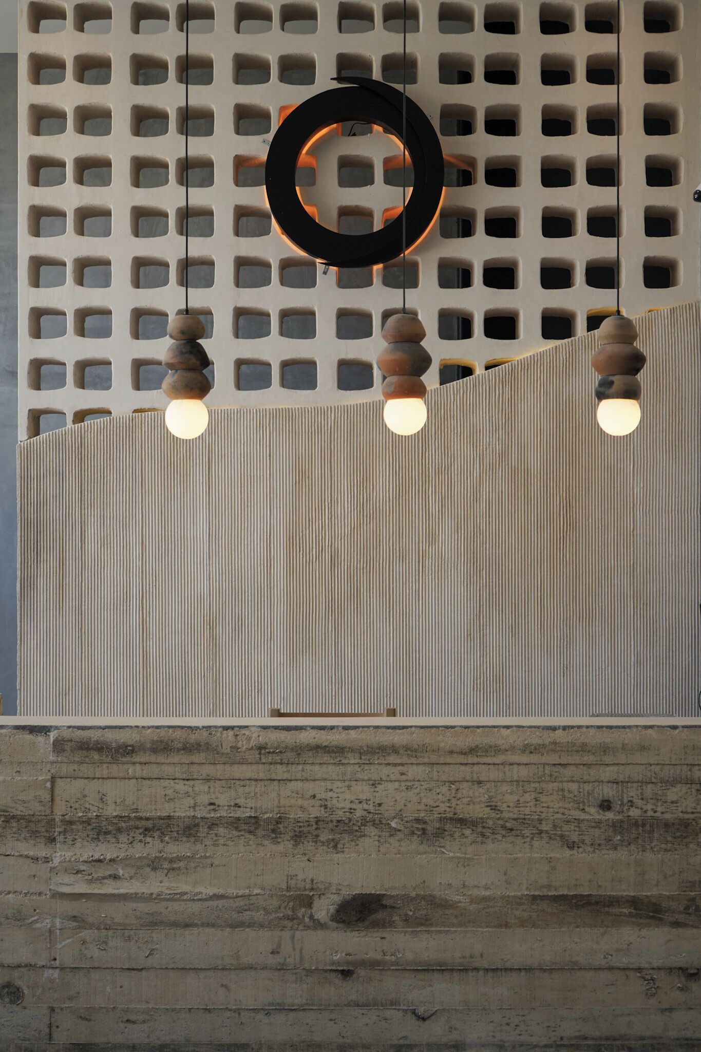 Un interior moderno con un diseño de pared geométrico, lámparas colgantes y un elemento decorativo circular.