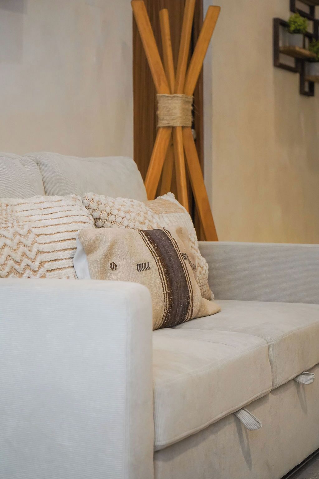 A light-colored sofa with a textured throw blanket and a decorative pillow.