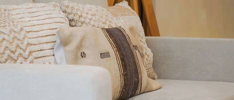 A light-colored sofa with a textured throw blanket and a decorative pillow.