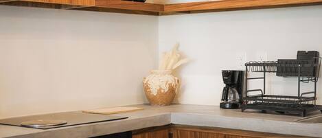 Une cuisine avec des meubles de rangement en bois, une machine à café et un égouttoir à vaisselle.