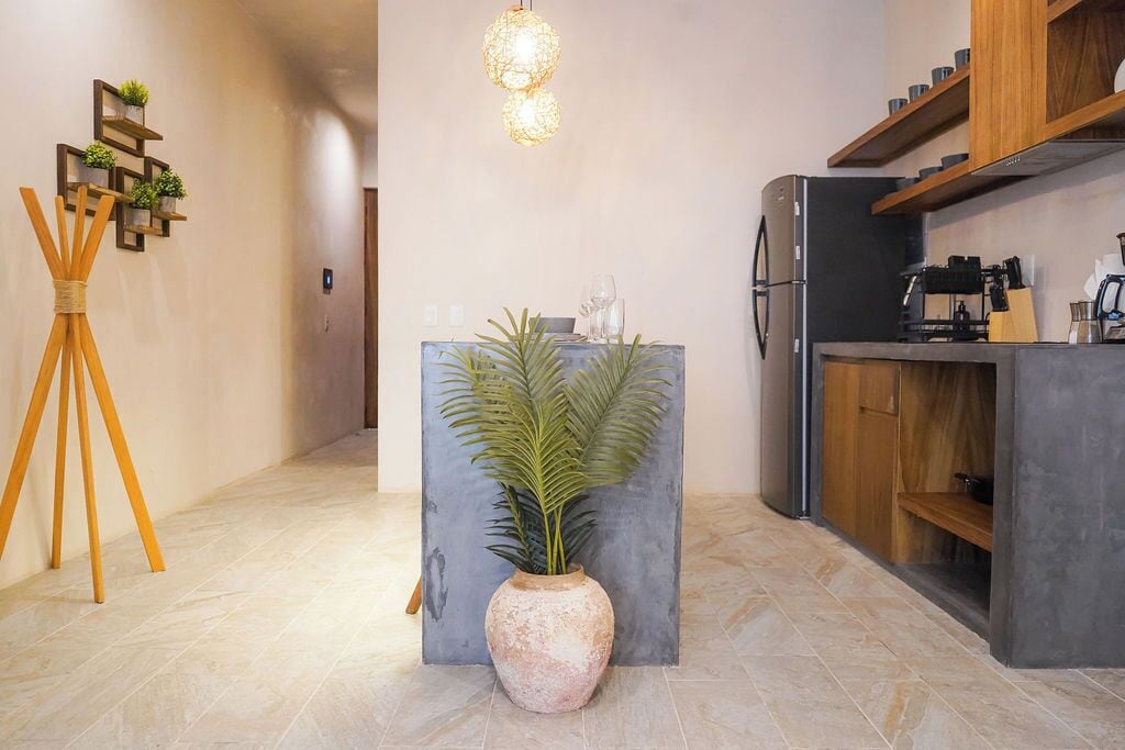 A modern kitchen with a built-in refrigerator, wooden cabinets, and a central island with a potted plant.