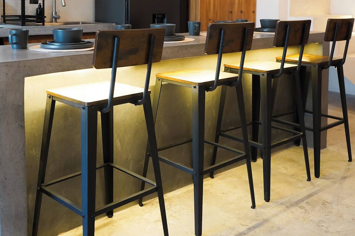 A modern kitchen with a central island, bar stools, and pendant lighting.