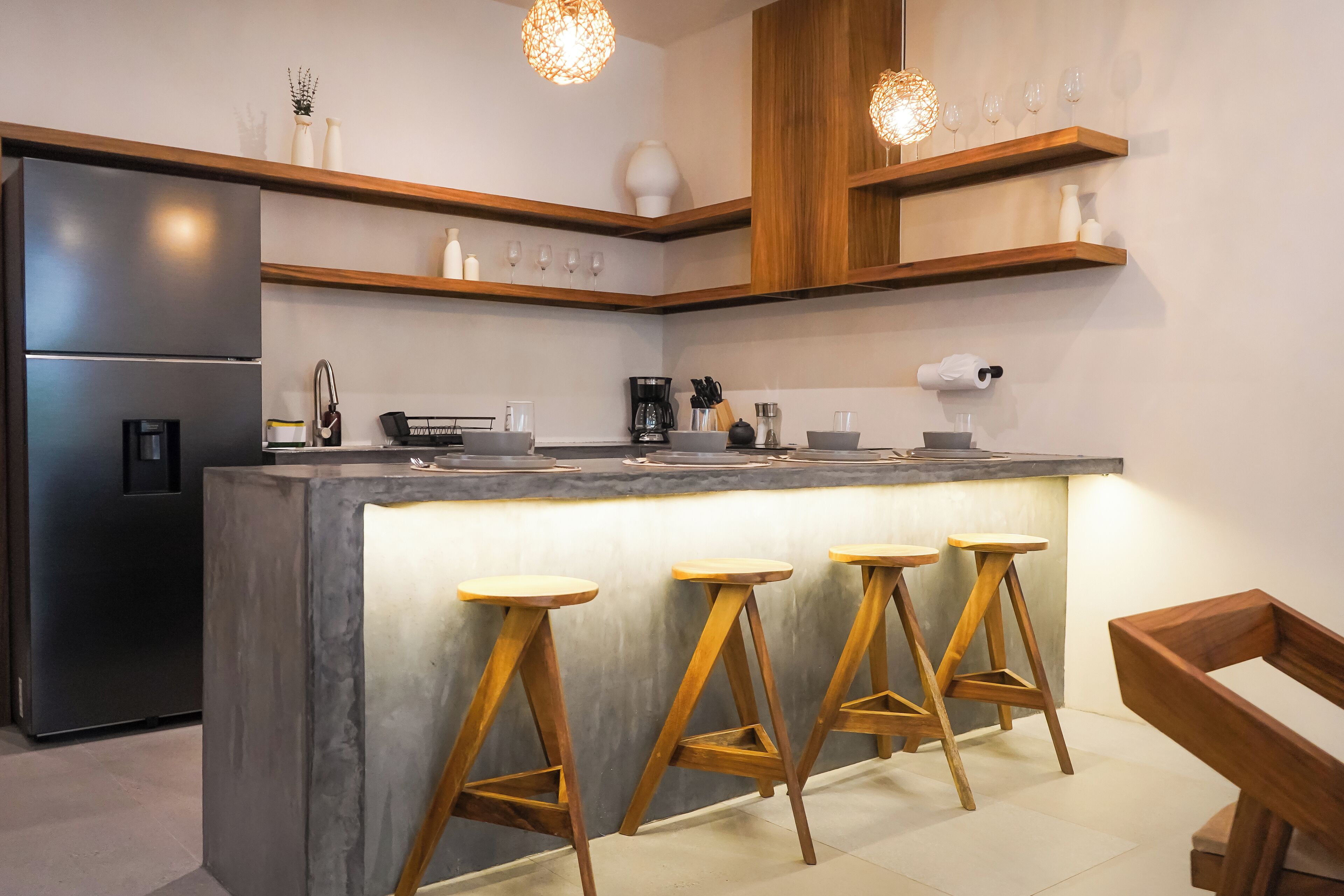 A modern kitchen with a central island, wooden stools, and built-in shelves.