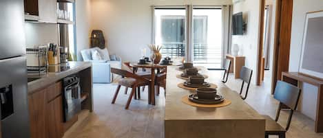 Una cocina moderna con una isla central, comedor con sillas y un amplio ventanal que proporciona luz natural.