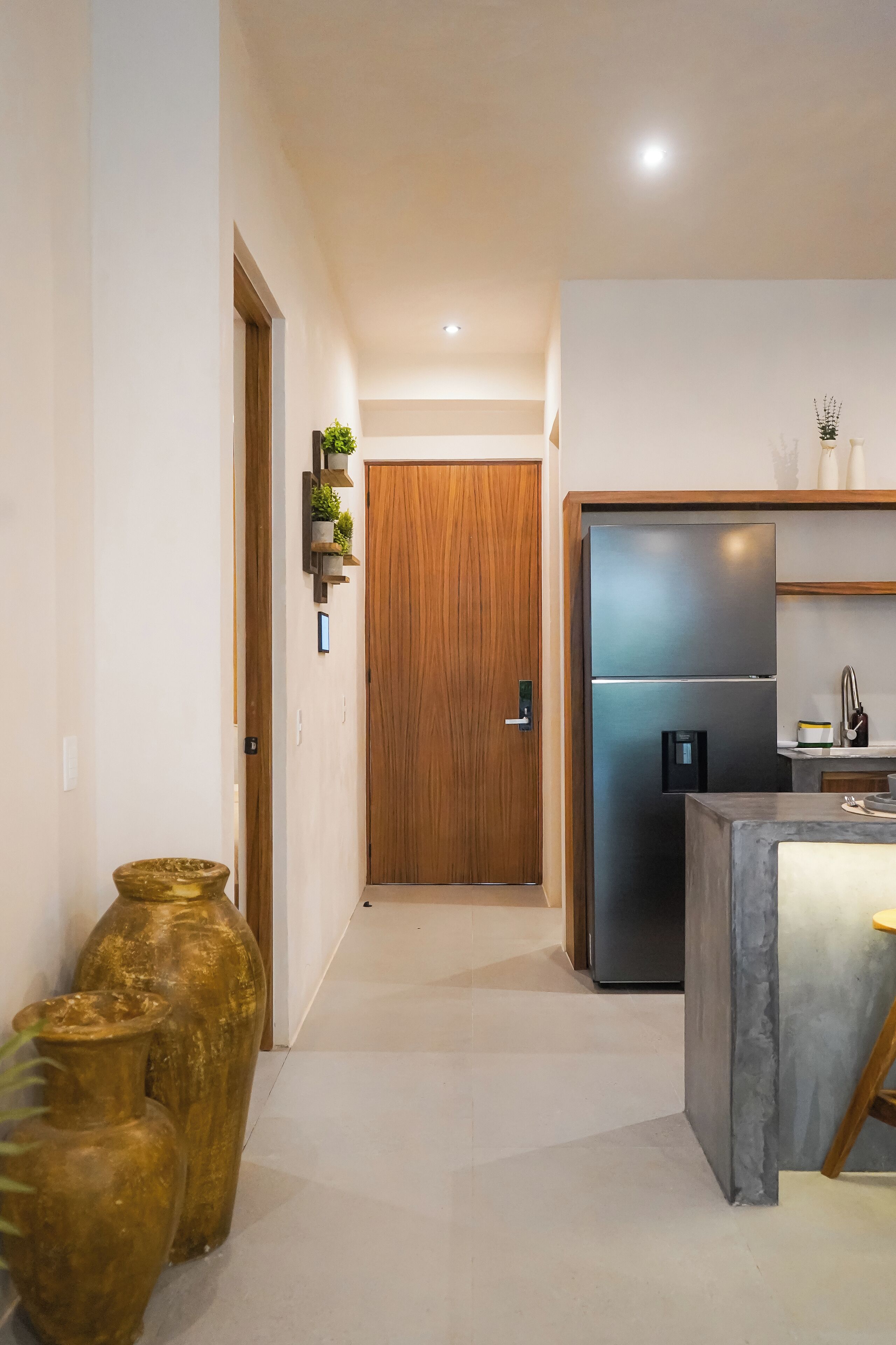 A modern kitchen with a stainless steel refrigerator, wooden cabinets, and a built-in island.