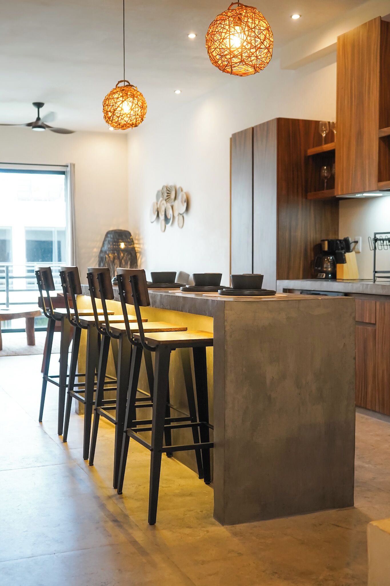Une cuisine moderne dotée d’un îlot central, de tabourets de bar, de luminaires suspendus et d’armoires en bois.