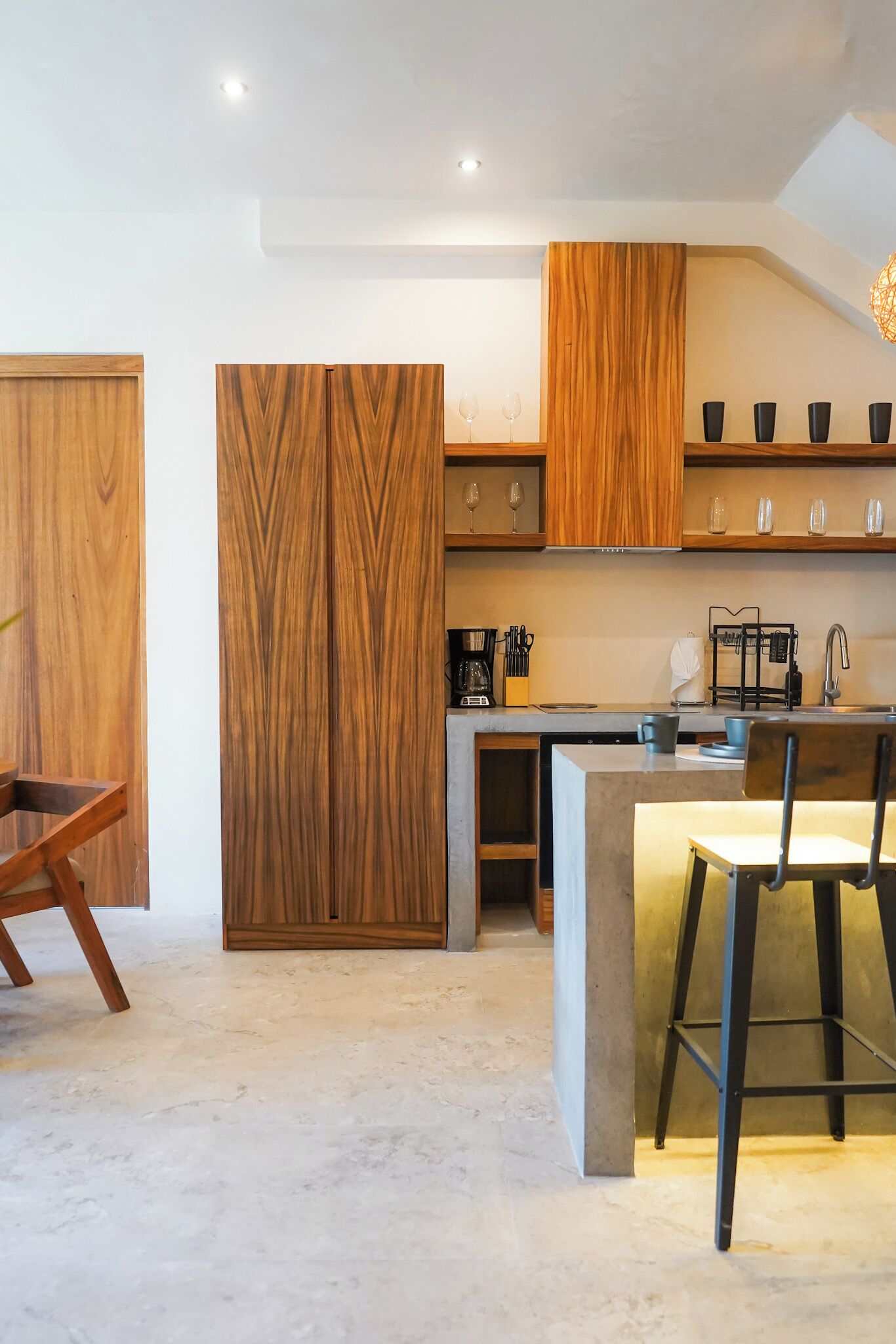 A modern kitchen with wooden cabinets, a central island with bar stools, and a built-in oven.