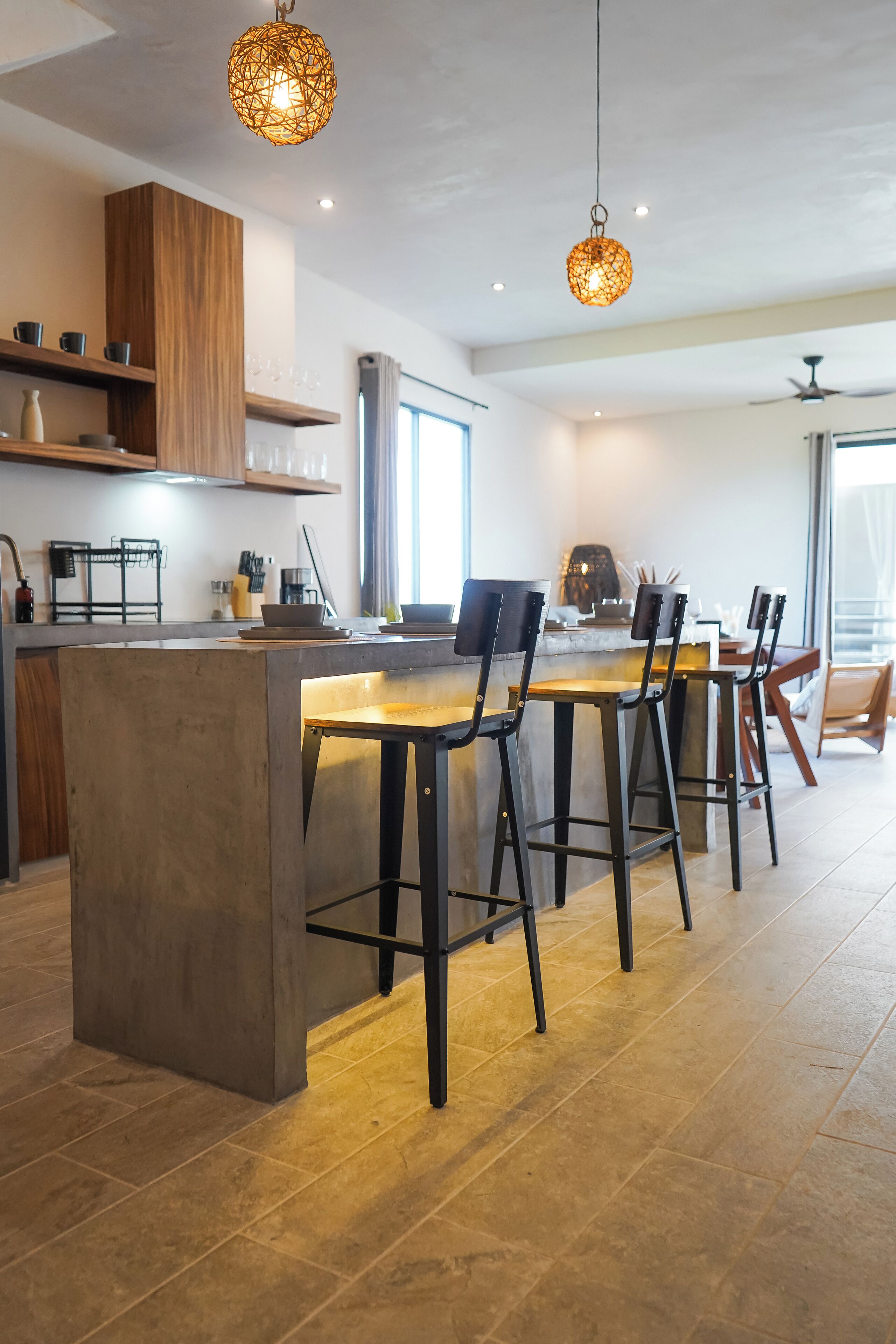 A modern kitchen with a central island, bar stools, and pendant lighting.