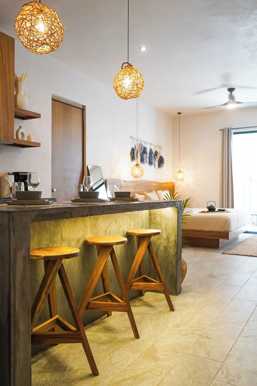 Une cuisine moderne avec un coin bar, des tabourets en bois et des luminaires suspendus.