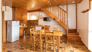 A kitchen with wooden cabinets, a refrigerator, a stove, and a dining table with chairs. - Gites Simond welcomes you to Arvieux in the heart of the Queyras Regional Park, (Arvieux)