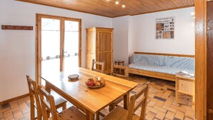 A wooden dining table with chairs, a bench, and a wooden cabinet in a room with tiled flooring and a wooden ceiling. - Gites Simond welcomes you to Arvieux in the heart of the Queyras Regional Park, (Arvieux)