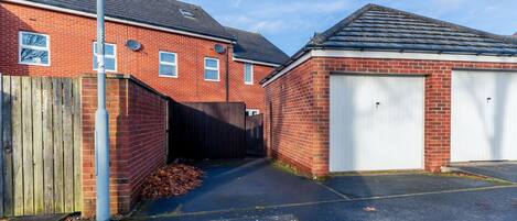 A residential area with a brick house, a garage, and a wooden fence.
