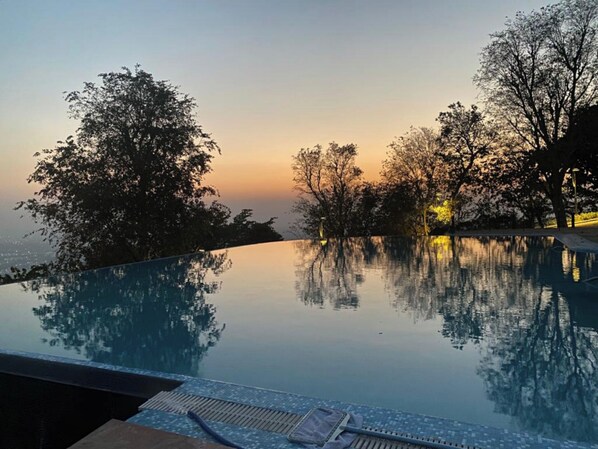 Una piscina sense fi amb vistes a arbres i un capvespre.