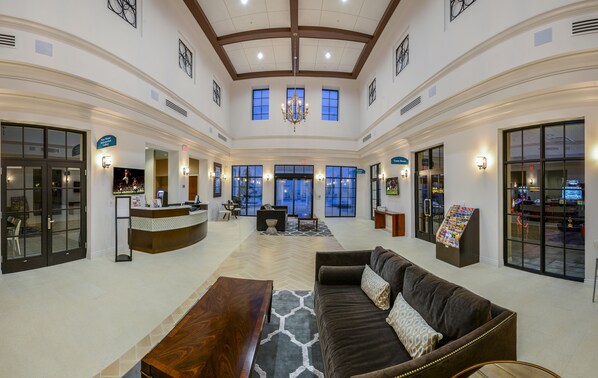 A spacious lobby with a reception desk, seating area, and large windows.