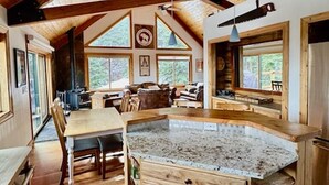 Een houten interieur met een keukeneiland, eettafel en stoelen.