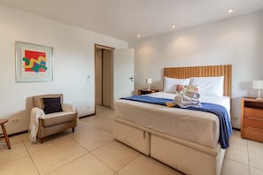 A hotel room with a bed, a chair, a bedside table, and a wall-mounted artwork. - Comfort and Tranquillity in Humait M404 (Rio de Janeiro)