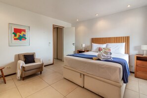 A hotel room with a bed, a chair, a bedside table, and a wall-mounted artwork. - Comfort and Tranquillity in Humait M404 (Rio de Janeiro)