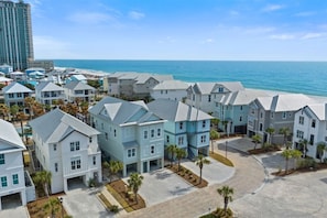 Una zona residencial costera con casas de varios pisos, una playa y un edificio alto al fondo.
