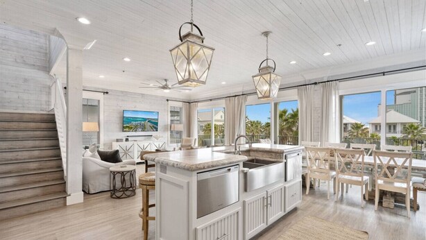 Una cocina amplia con una isla central, armarios blancos e iluminación colgante.