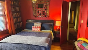 A room with a bed, a bookshelf, a lamp, and a door.