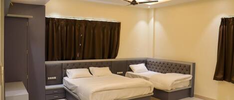 Ein modernes Schlafzimmer mit einem großen Bett, zwei kleineren Betten, einem Deckenventilator und einem Fenster mit Vorhängen.