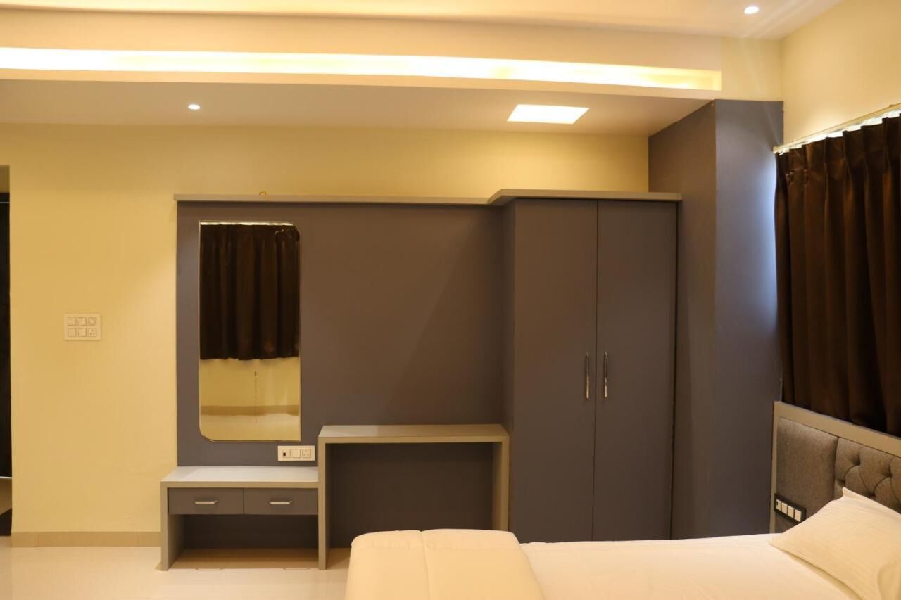 A modern bedroom with a bed, a wardrobe, a vanity with a mirror, and a small table.