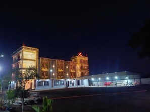 A multi-story building with a modern design, featuring a glass facade and illuminated exterior. - Hotel Panna Shree (Ujjain)